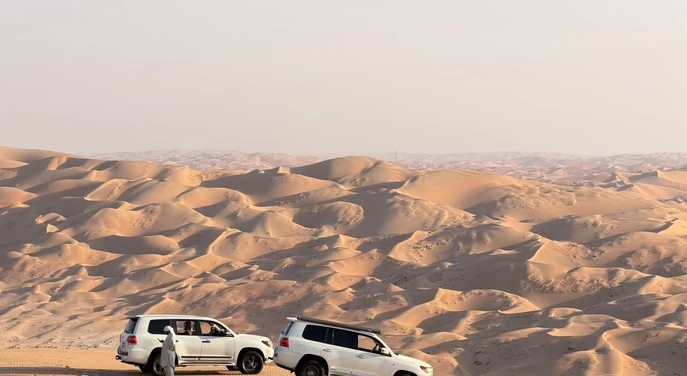 Two Toyota Land Cruisers stopped above the vast Liwa Empty Quarter dunes