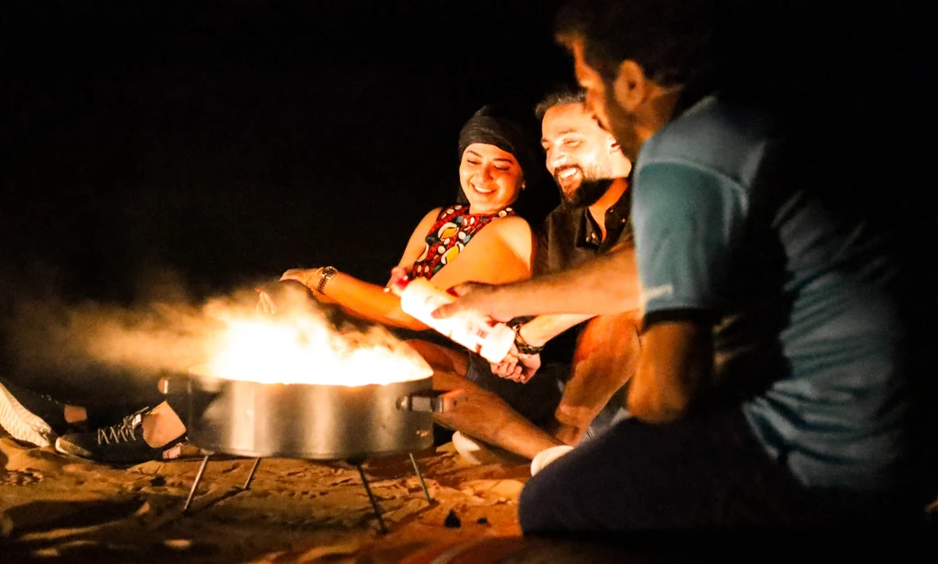 Guests relaxing around a campfire during an overnight Liwa desert safari