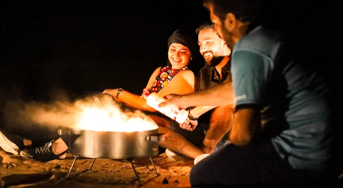 Guests relaxing around a campfire during an overnight Liwa desert safari