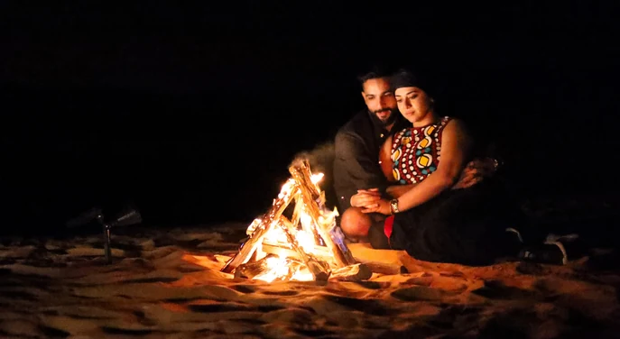 Couple sitting beside a bonfire during their Liwa overnight camping experience