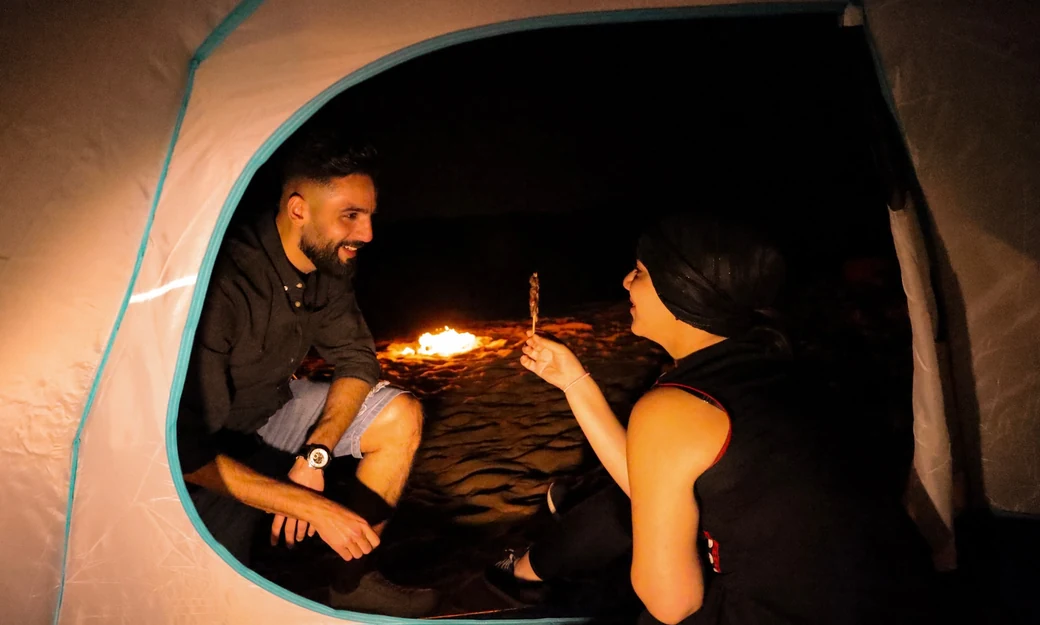 Couple relaxing inside their tent during an overnight camp in the Liwa desert