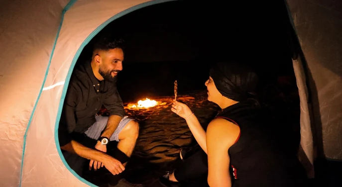 Couple relaxing inside their tent during an overnight camp in the Liwa desert