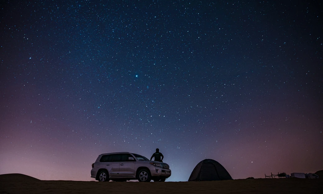 Toyota Land Cruiser and desert tent beneath a star-filled Empty Quarter night sky