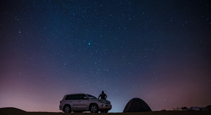 Toyota Land Cruiser and desert tent beneath a star-filled Empty Quarter night sky