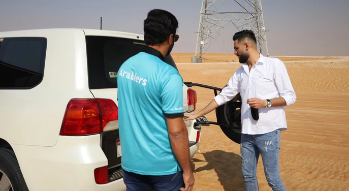 Arabiers desert guide briefing a guest beside the tour Land Cruiser before the Liwa drive