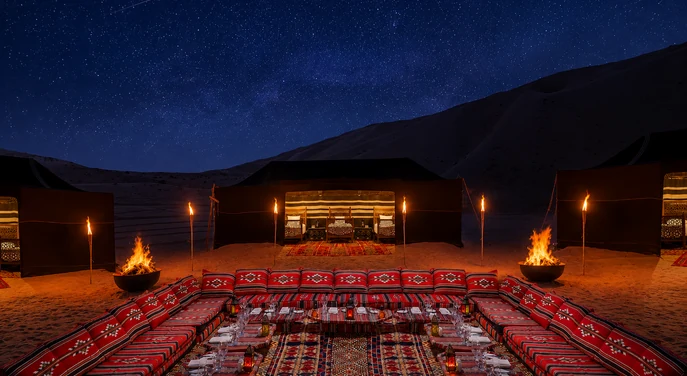 Private torch-lit desert dining camp under a star-filled sky near Qasr Al Sarab