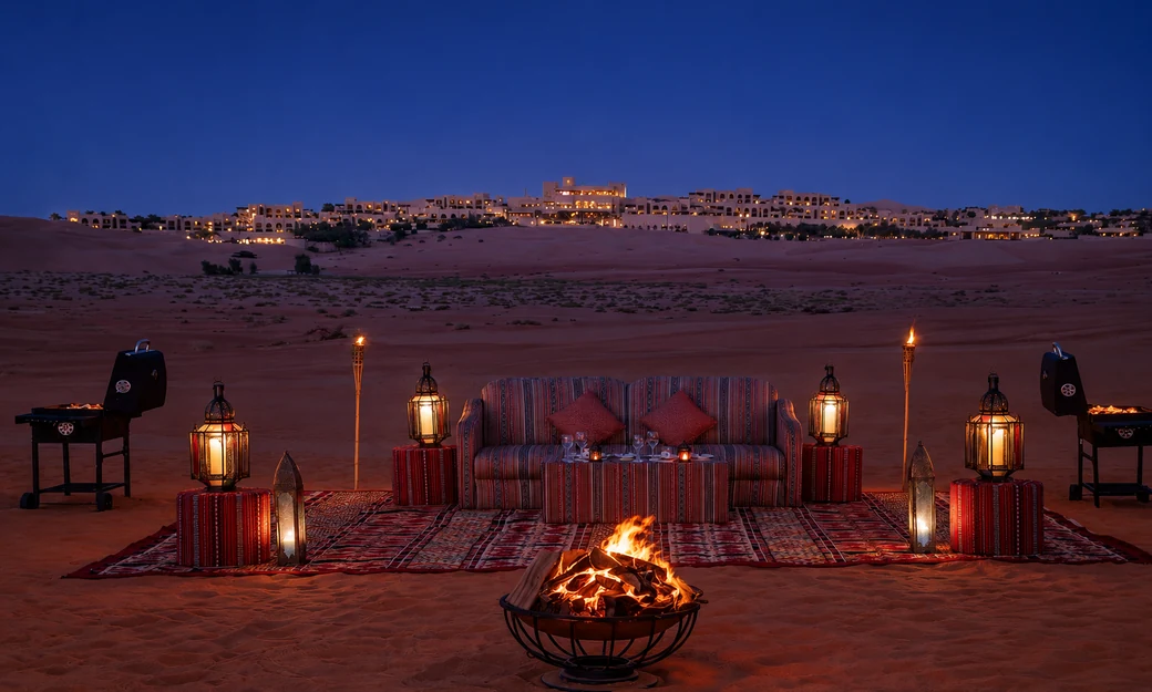 Private bonfire dining setup overlooking Qasr Al Sarab resort at night
