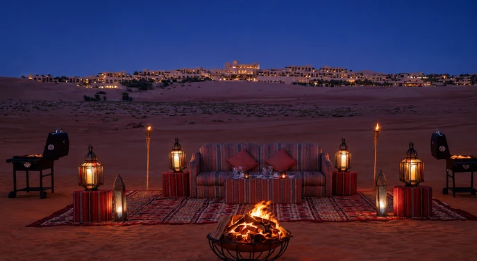 Private bonfire dining setup overlooking Qasr Al Sarab resort at night