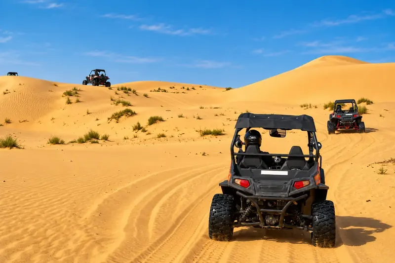 Guest driving a dune buggy up the dunes with the guide ahead in Al Khatim, Abu Dhabi
