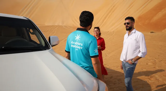 Arabiers guide briefing guests beside a private desert safari vehicle