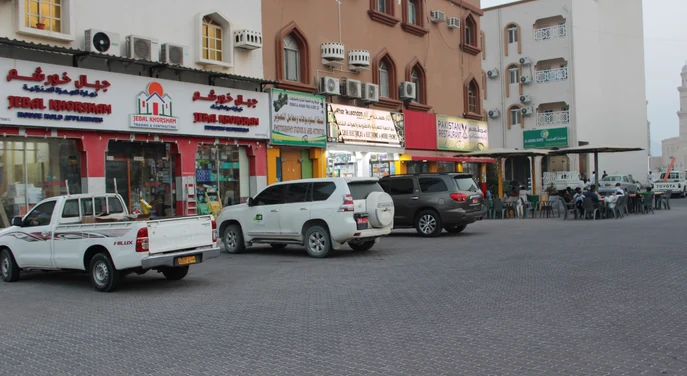 Street view with shops and parked vehicles in Khasab city