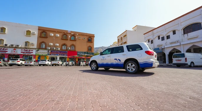 Tour vehicle parked in Khasab city with shops and local buildings