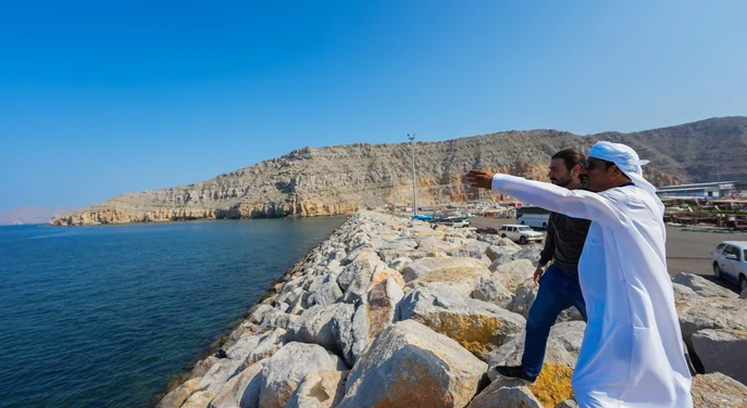 Local guide showing a traveller the Khasab harbour and mountain coastline