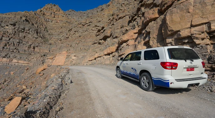 4WD vehicle driving along a rugged mountain road in Musandam
