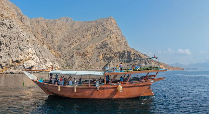 Guests aboard a traditional dhow cruising through the rugged fjords of Khasab