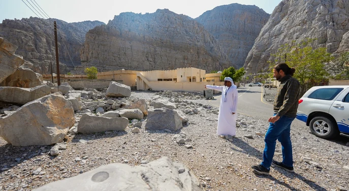 Local guide and traveller exploring a rocky mountain village near Khasab