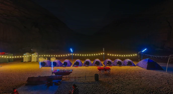 Night overview of a remote Musandam beach camp with tents and lights