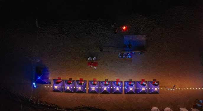 Aerial view of an overnight beach camp with tents and lights in Musandam