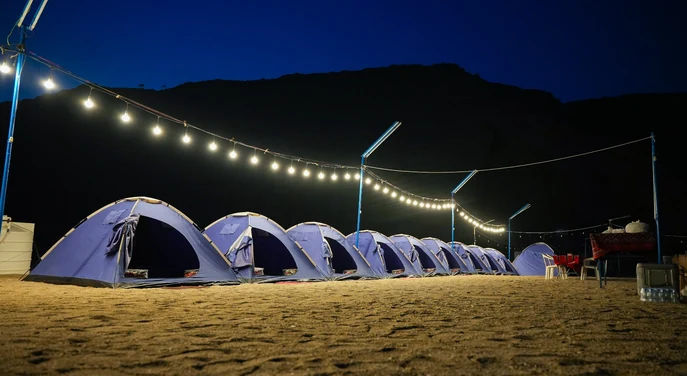 Row of illuminated tents at a Musandam overnight beach camp