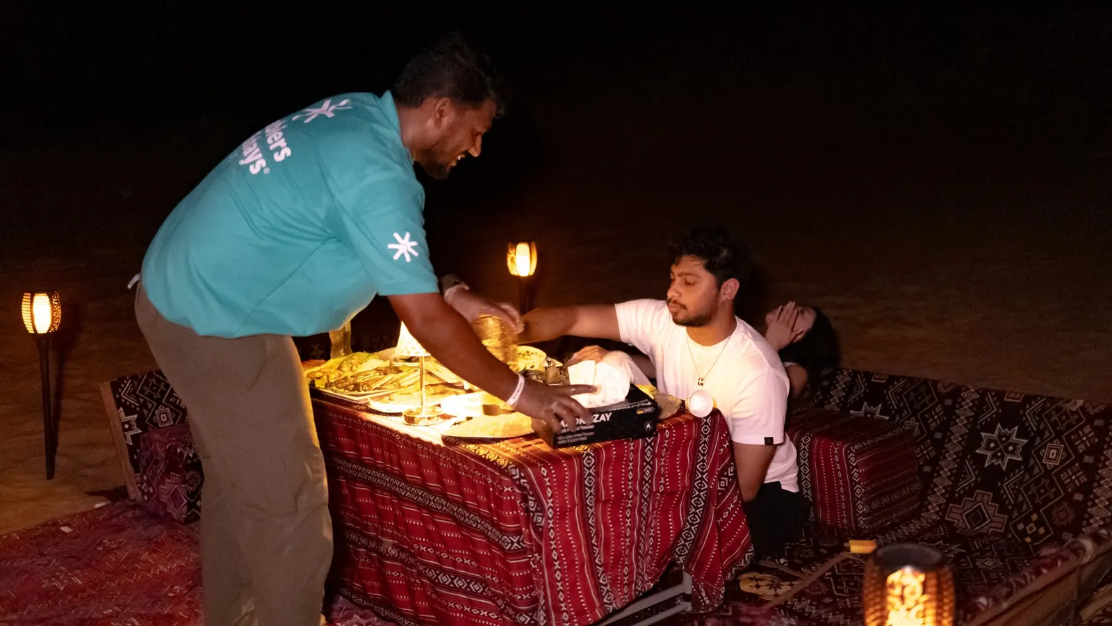 Arabiers host serving dinner to a guest at a private desert setup