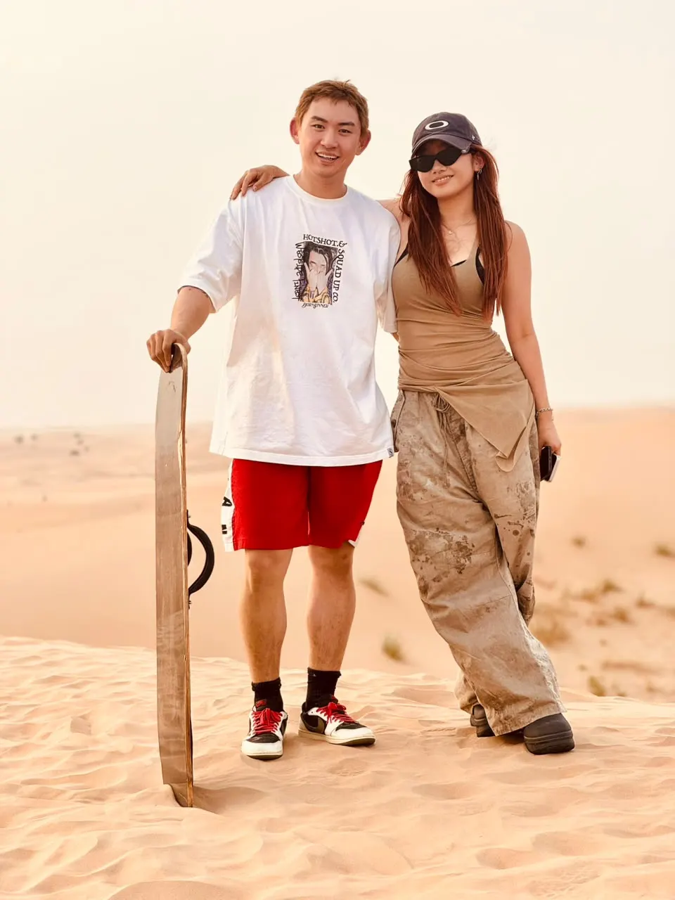 Couple holding a sandboard after sandboarding on the Abu Dhabi dunes