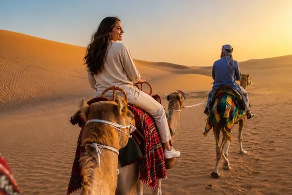 Guests camel trekking across Abu Dhabi desert dunes at sunset
