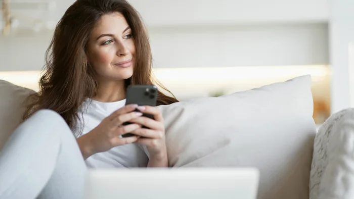 Woman using a smartphone at home while arranging a Dubai express visa from inside the UAE