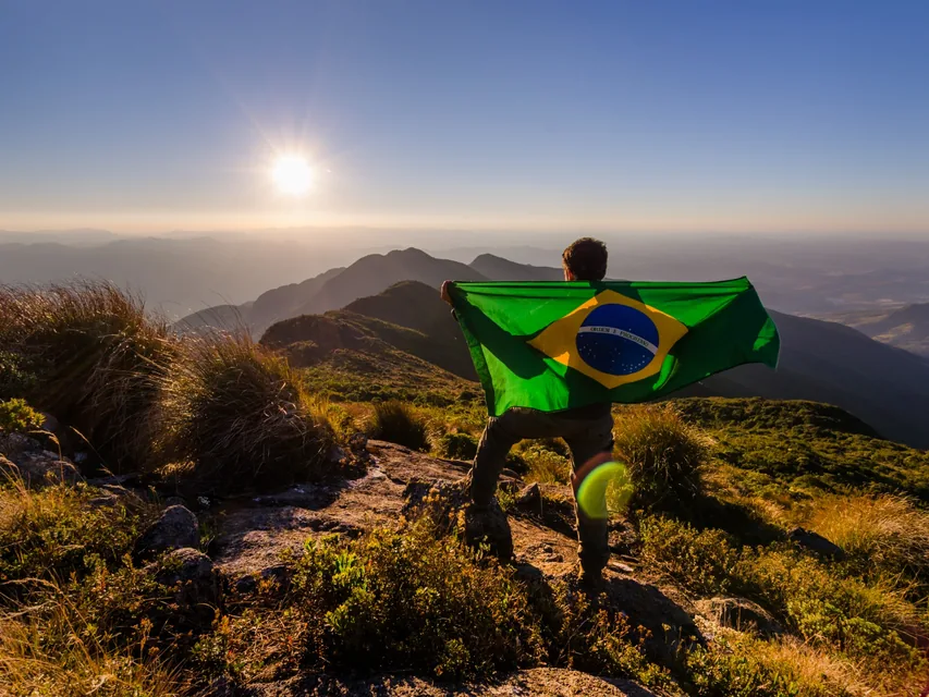 Traveller holding the Brazilian flag on a mountain during a visit to Brazil