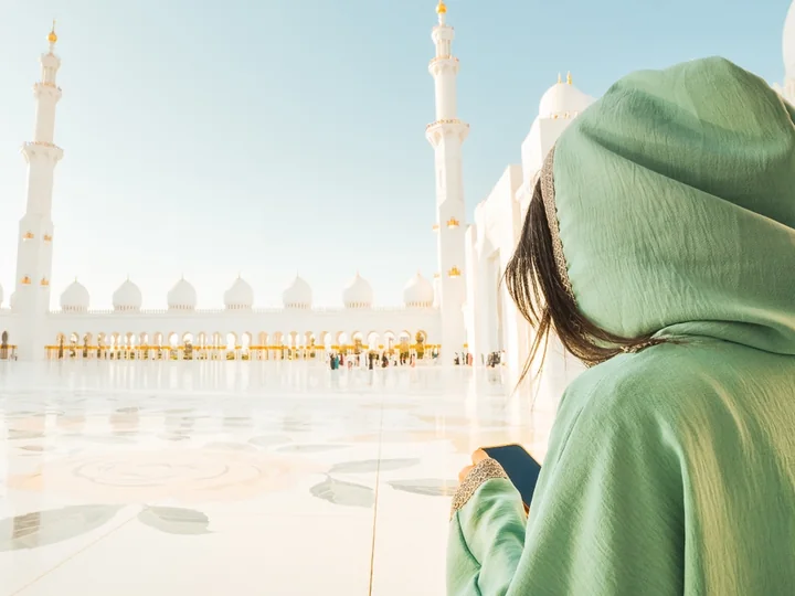 Visitor in Abu Dhabi checking UAE visa details during a mosque visit