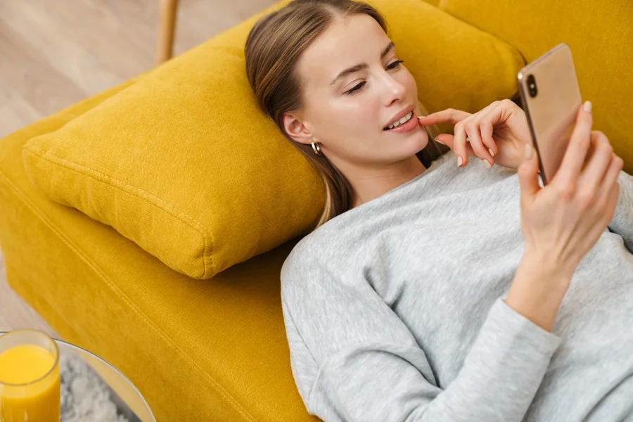 Woman at home using a smartphone while arranging a UAE visa change without exit