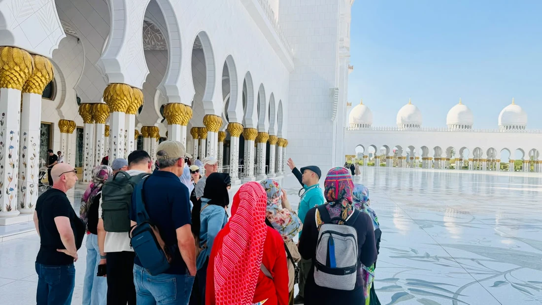 Visitors walking across Sheikh Zayed Grand Mosque courtyard